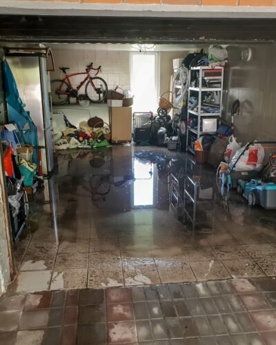 Photo of flooded garage after heavy rain. Wet floor and floating thing in house after flood